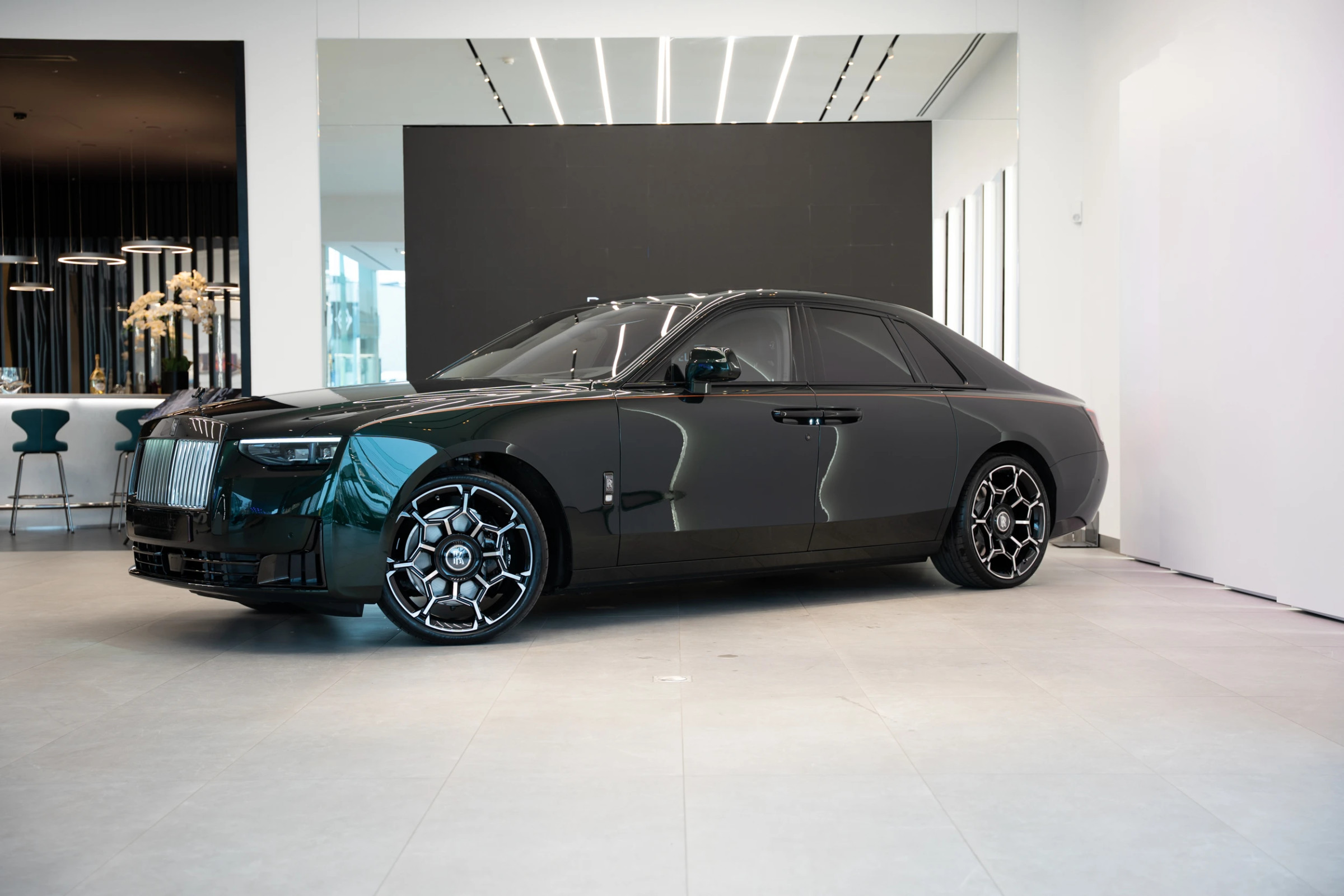 Rolls-Royce Black Badge Ghost 2026 em Dark Emerald — frente 3/4 no showroom oficial Rolls-Royce Brussels